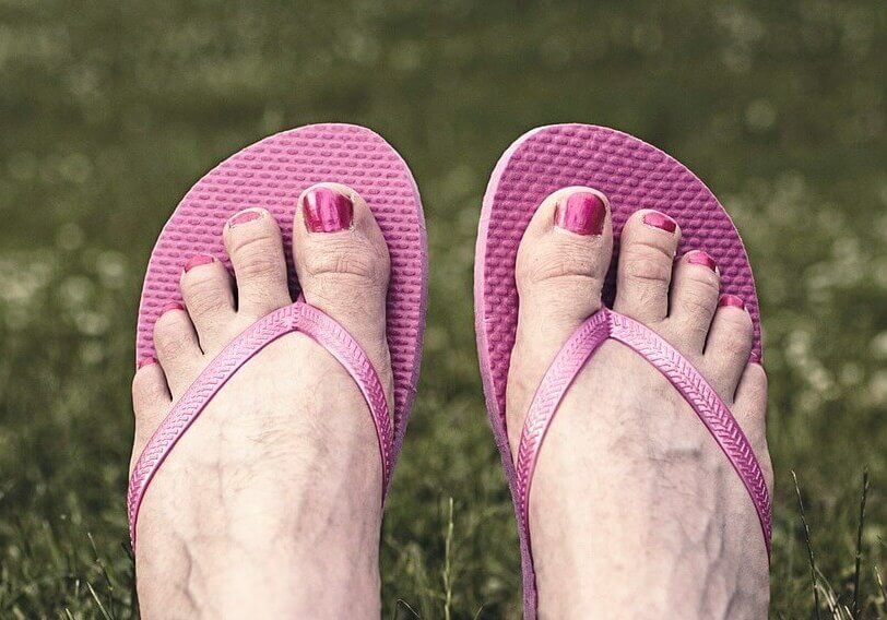 Elderly feet with pink toenails wearing pink flip flops